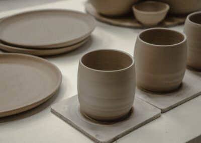 Showcasing a collection of handmade ceramic mugs and plates with a minimalist design.