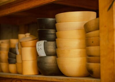 A collection of handcrafted wooden and ceramic bowls stacked on a shelf, showcasing craftsmanship.