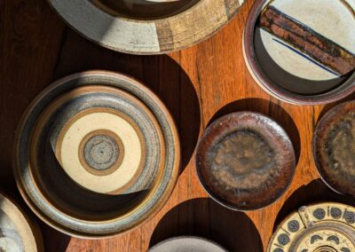 A collection of various ceramic bowls arranged beautifully on a wooden surface with natural light casting shadows.